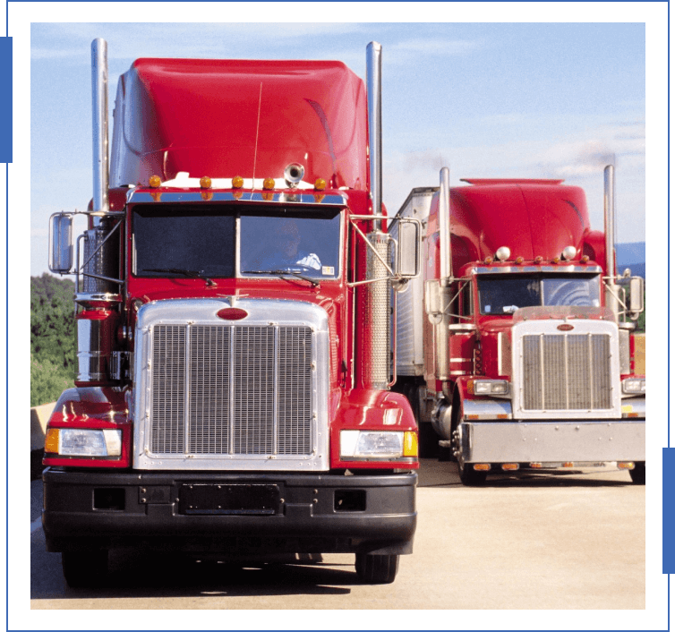 Two red trucks are parked on the side of a road.