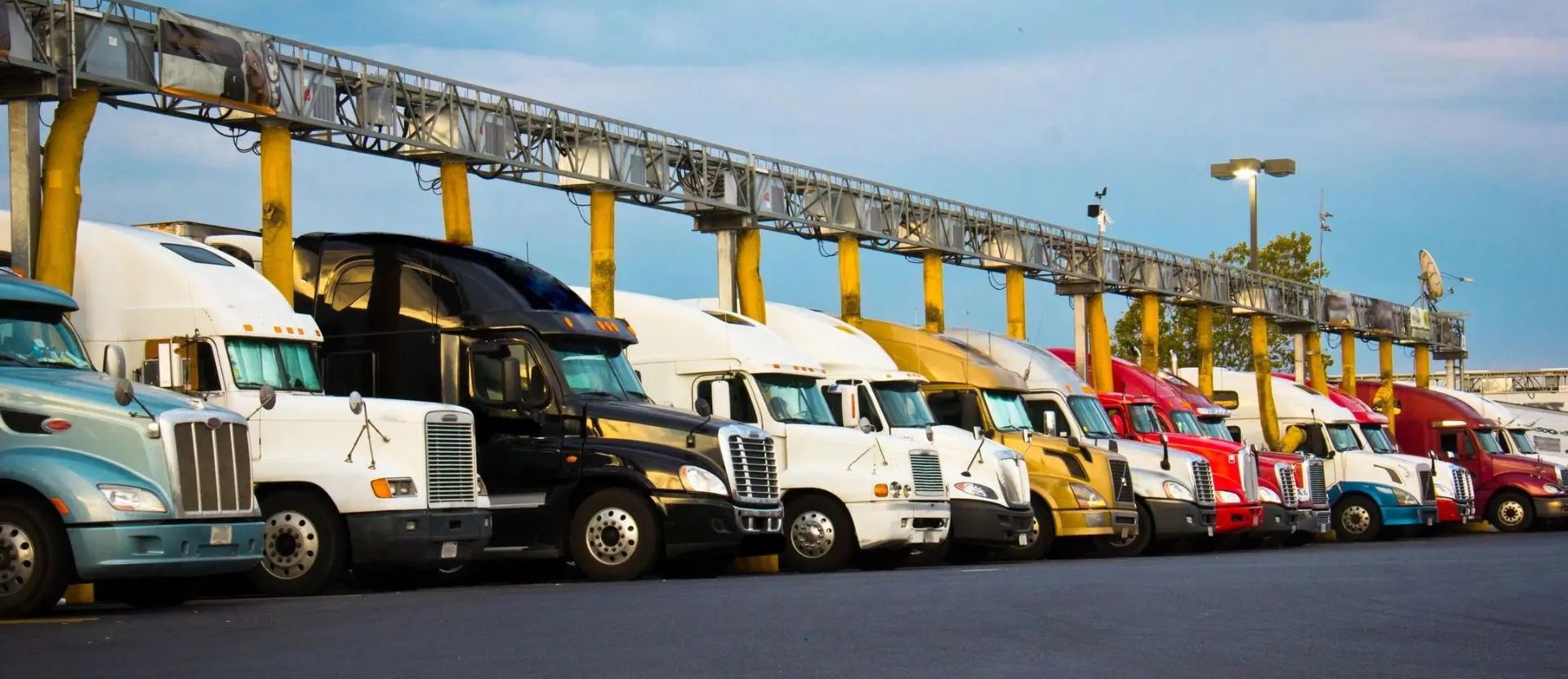 A line of trucks parked in front of a yellow bridge.
