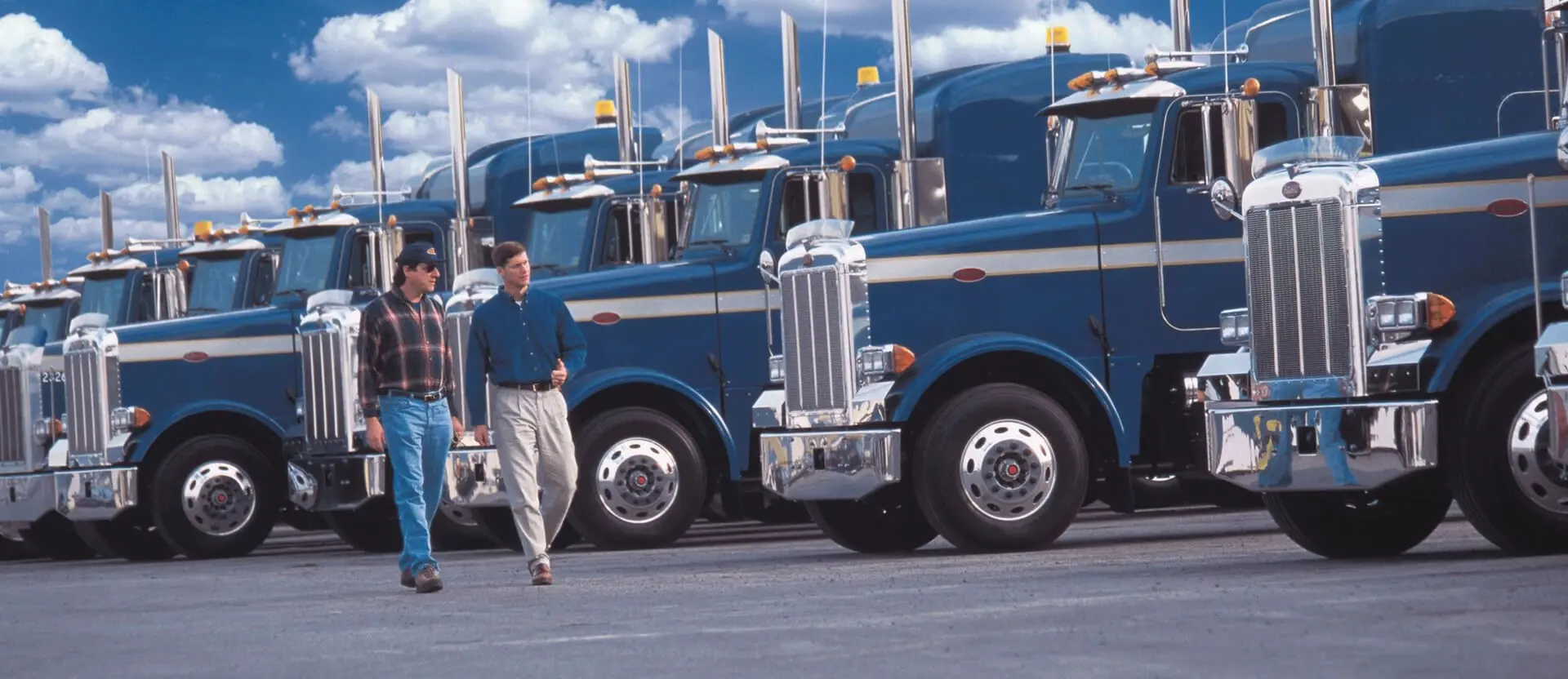 A man walking in front of several blue trucks.